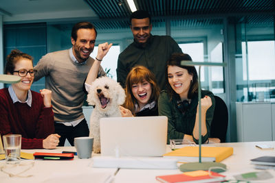 Excited business team with dog at desk in creative office