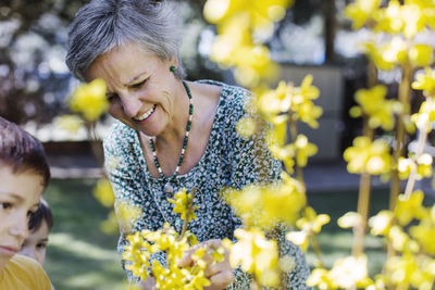 Boys looking at grandmother pruning flowers at yard