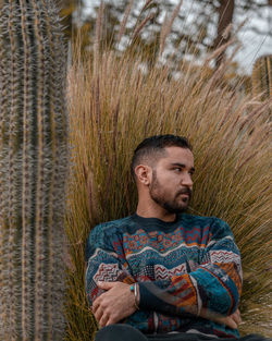 Young man chilling out on a field with big cactus on the side