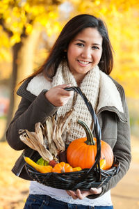 Portrait of a smiling young woman standing by pumpkin