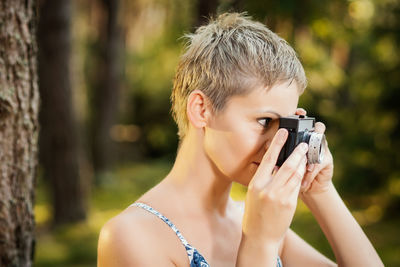 Close-up of woman photographing with camera in forest