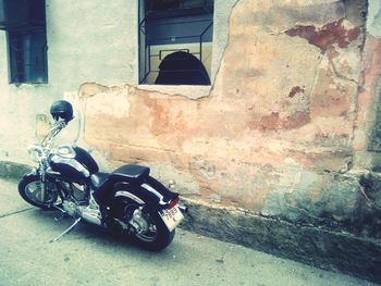 Bicycle parked on street by wall of building