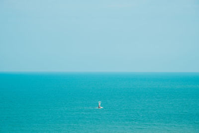 A lighthouse in the middle of the blue sea and sky.