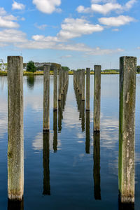 Wooden posts in sea against sky