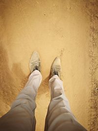 Low section of man standing on sand