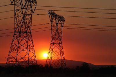 Low angle view of silhouette electricity pylon against sky during sunset