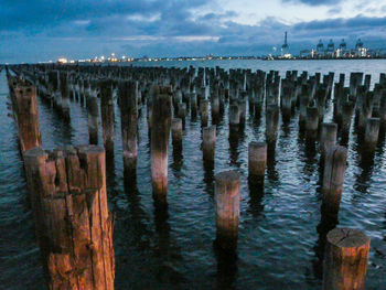 Wooden posts in sea against sky