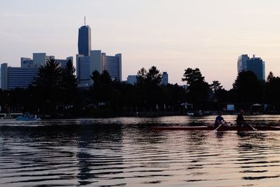 Man sailing on river in city at sunset