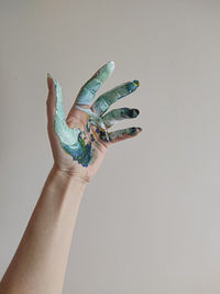Cropped hand of woman gesturing against white background with paint on hands