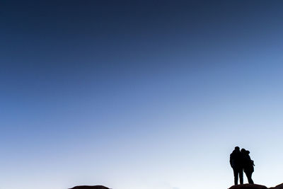 Silhouette people walking against clear blue sky