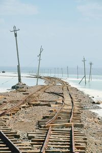 Broken railroad tracks passing by lake against clear sky