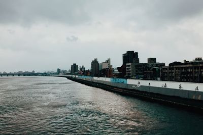 Sea by buildings against sky in city