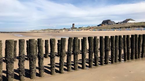 Wooden posts on beach against sky