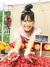 Portrait of smiling young woman buying fruits in market