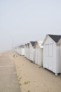 Beach huts by buildings against clear sky