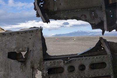 Close-up of airplane flying over landscape against sky