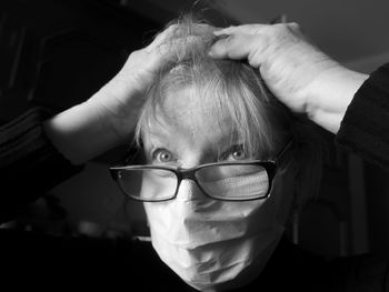 Close-up of senior woman with hands in hair wearing pollution mask looking away