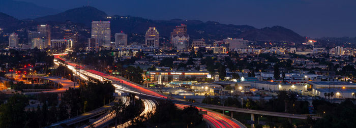 High angle view of light trails on road amidst buildings at night