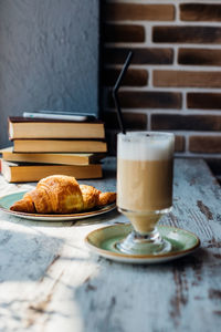 Latte in a tall glass against the background of a stack of books.the drink is on the table in a cafe