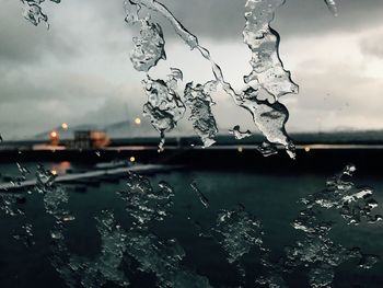 Close-up of wet window against sky