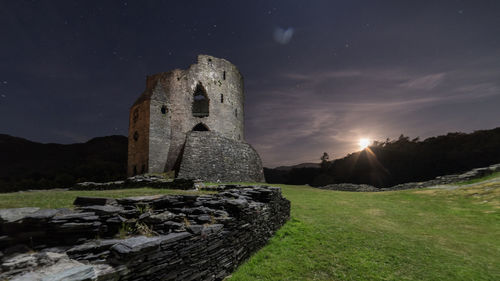 Old ruin against sky on field at night