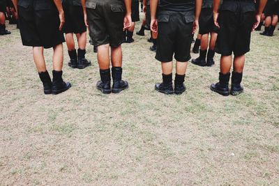 Low section of children wearing uniforms standing on land