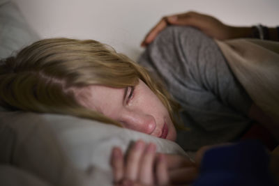 Crying young woman lying in bed