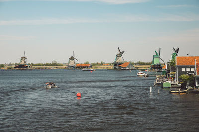 Windmills by lake against sky