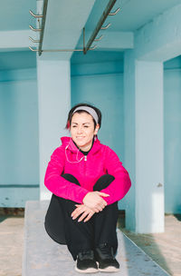 Portrait of smiling woman standing against wall