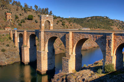 Arch bridge over river against sky