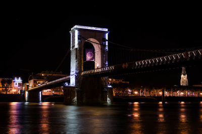 Illuminated bridge over river at night