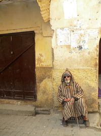 Portrait of woman sitting on old wall