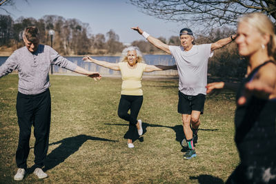 Senior men and woman with arms outstretched learning in exercise class at park