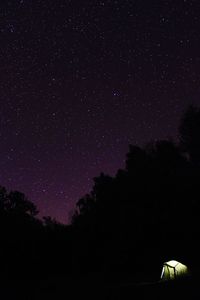 Illuminated tent in forest against star field