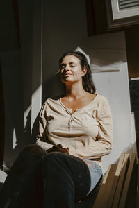 Smiling woman enjoying sunlight during home renovation