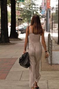 Rear view of woman walking on footpath in city