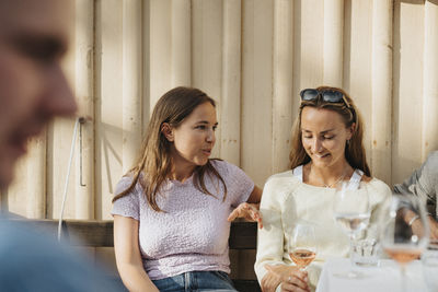 Young woman talking to female friend during dinner party at cafe