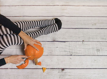 Low section of person holding orange on table