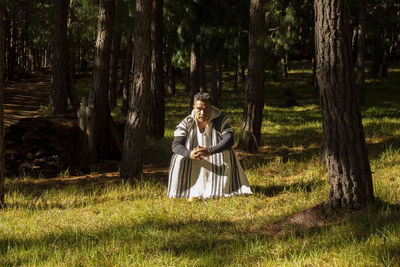 Man standing on field against trees in forest
