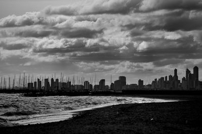 Sea by buildings against sky in city