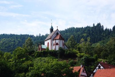 Low angle view of church on green mountain against sky