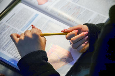 Cropped image of woman studying book at home