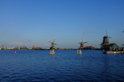 Traditional windmills by river against clear sky