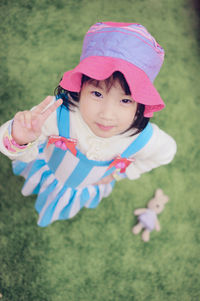 High angle portrait of girl gesturing peace sign on field