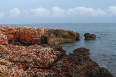 Rocks on sea shore against sky