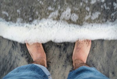 Low section of man standing at waters edge