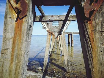 Old wooden pier on sea against sky