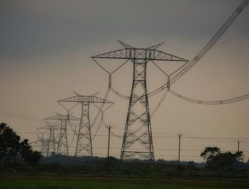 Low angle view of electricity pylon on field against sky