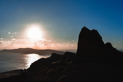 Silhouette rocks on sea against sky during sunset