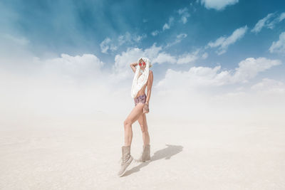 Woman standing at beach against sky